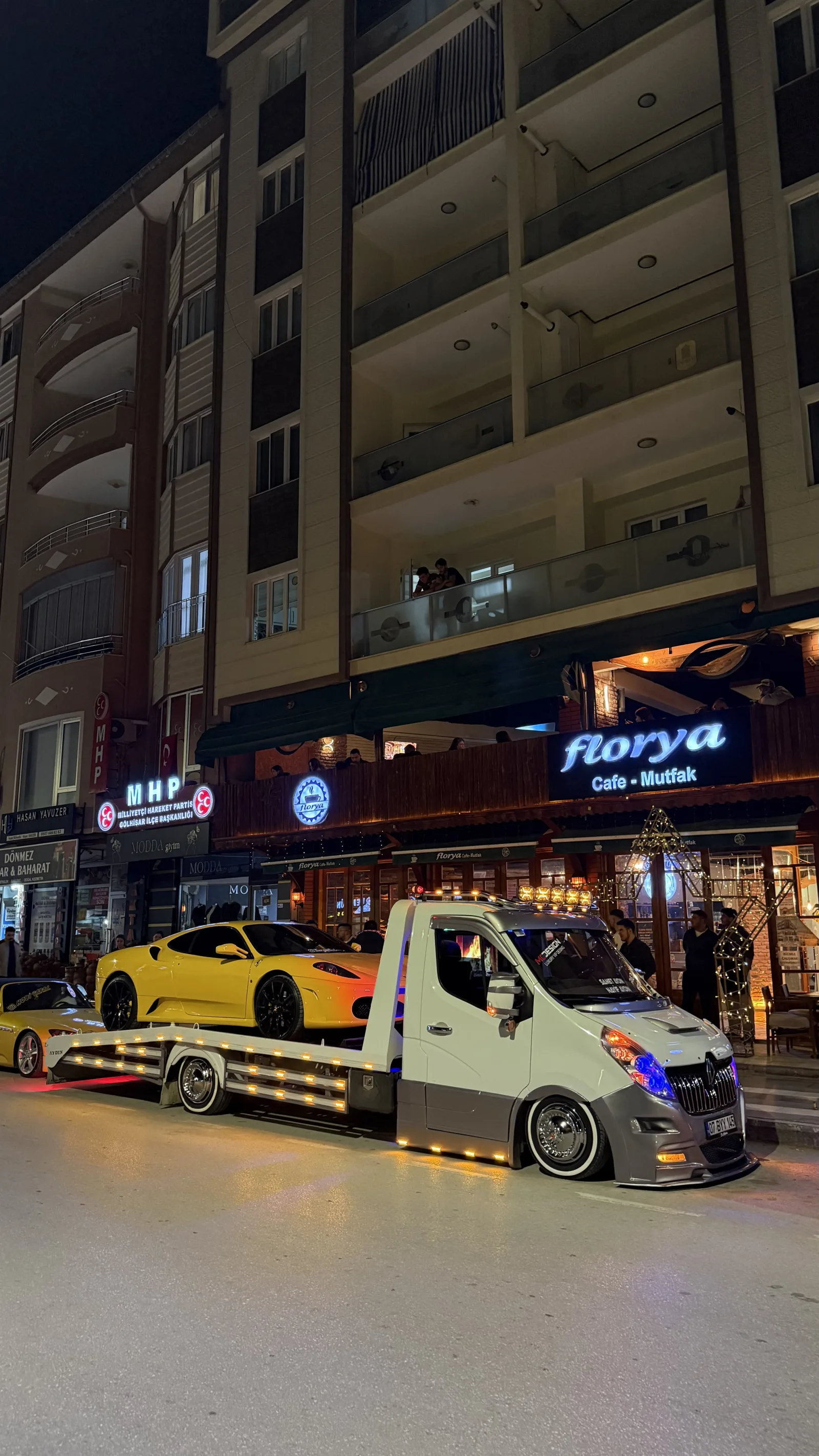 Gece şehir içinde platform çekici üzerinde sarı spor otomobil