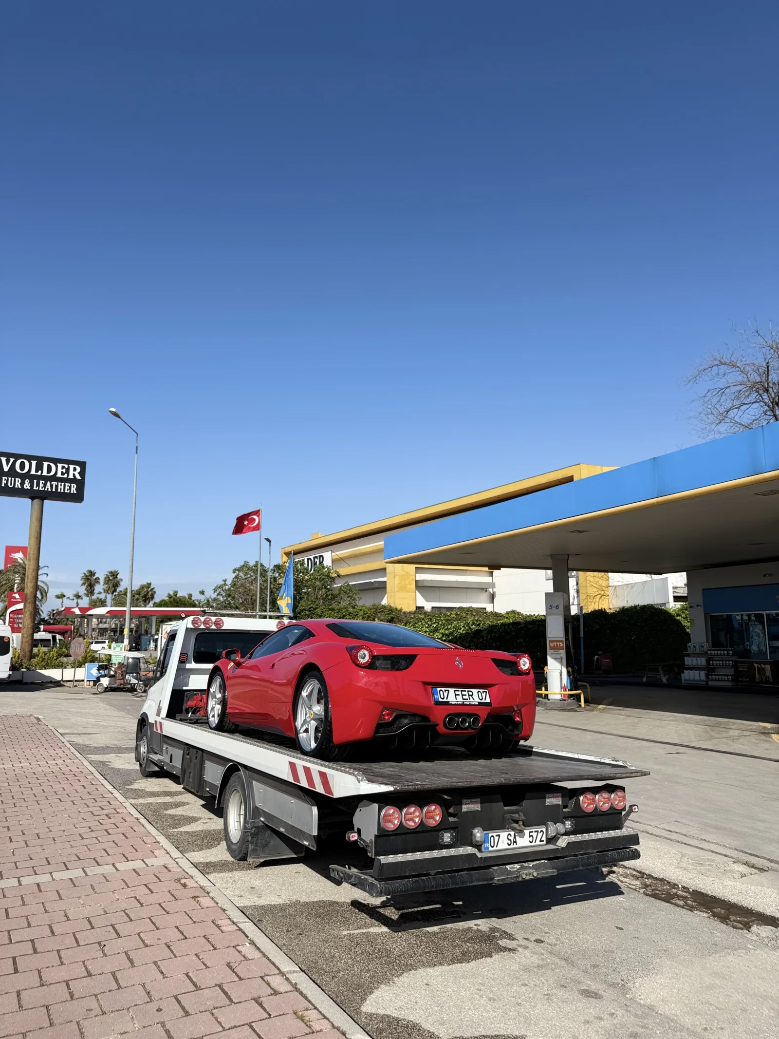 Akaryakıt istasyonu yanında platform çekici üzerindeki kırmızı spor otomobil