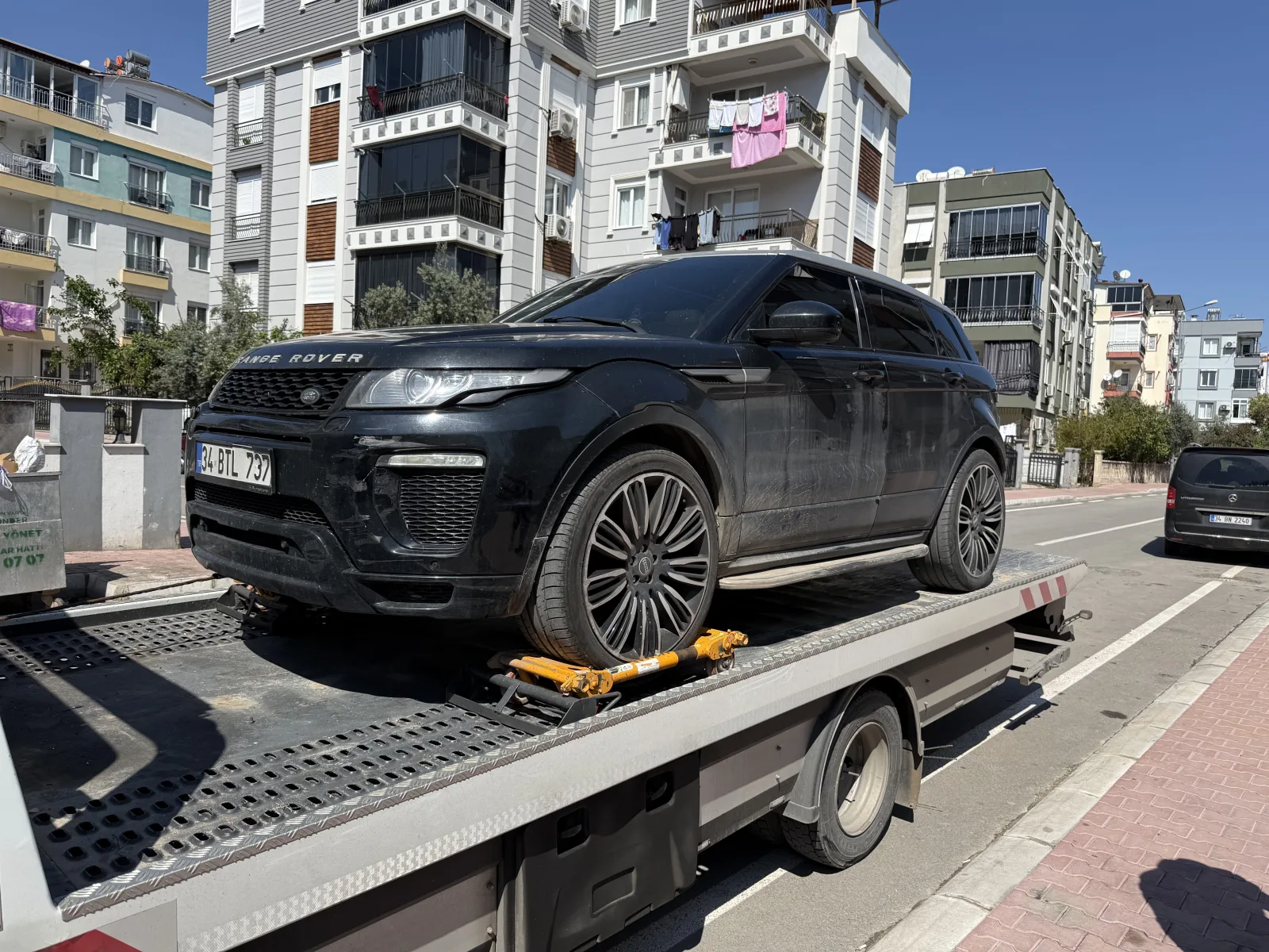 Güneşli havada platform çekici üzerinde sabitlenmiş siyah SUV